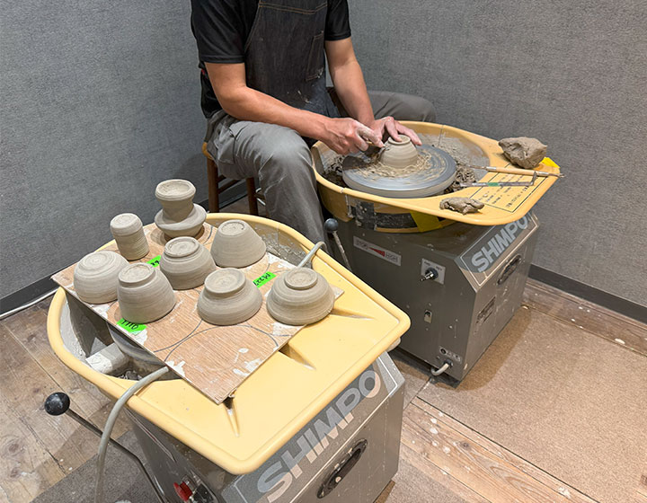 The instructor is neatly finishing the base of a piece made by a previous workshop participant. He makes the pieces exceptionally easy to use as tableware.
