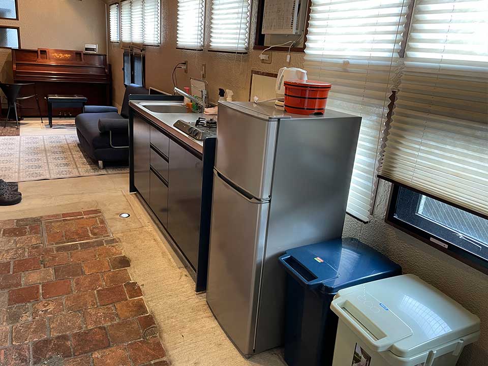 The kitchen, monitor, and sofa are lined up on the right side of the room as you enter through the entrance, and the piano is located at the back of the room.